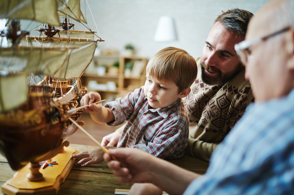 Three generations building a model ship symbolizing Generational Wealth